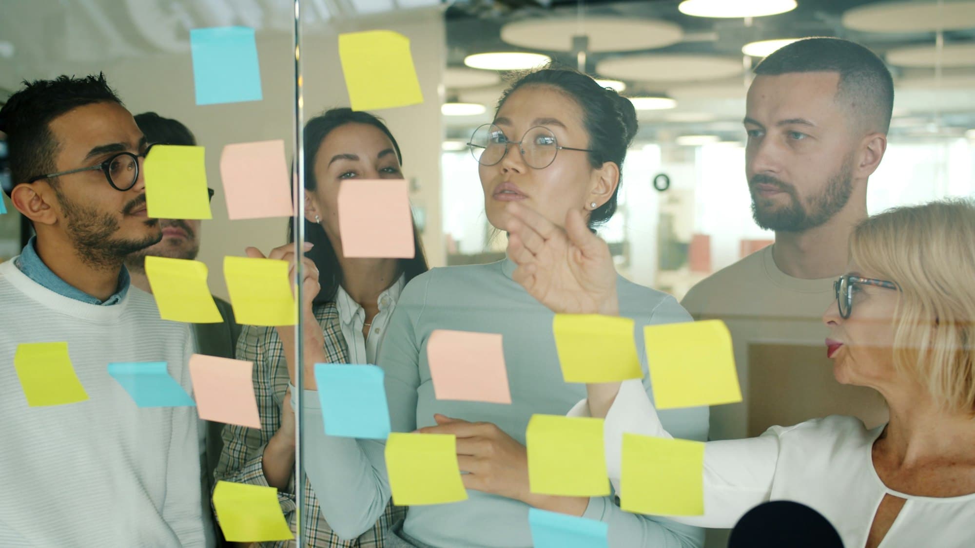 Team brainstorming with sticky notes on glass